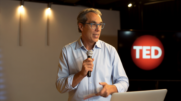 Un avatar de A. Cambronero impartiendo una charla TED, con micrófono en mano.